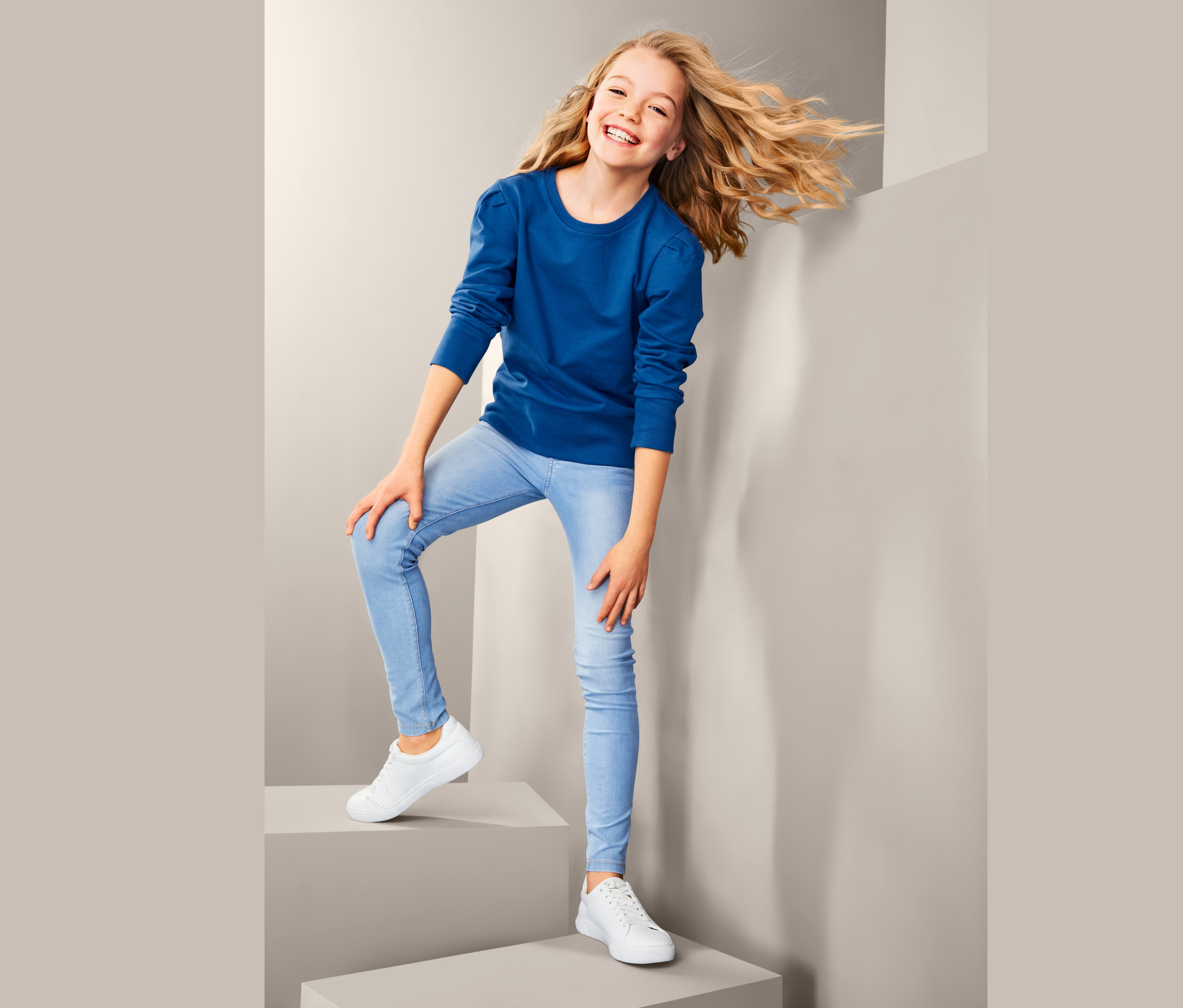 Lächelndes Mädchen posiert auf Stufen mit einem Sweatshirt.