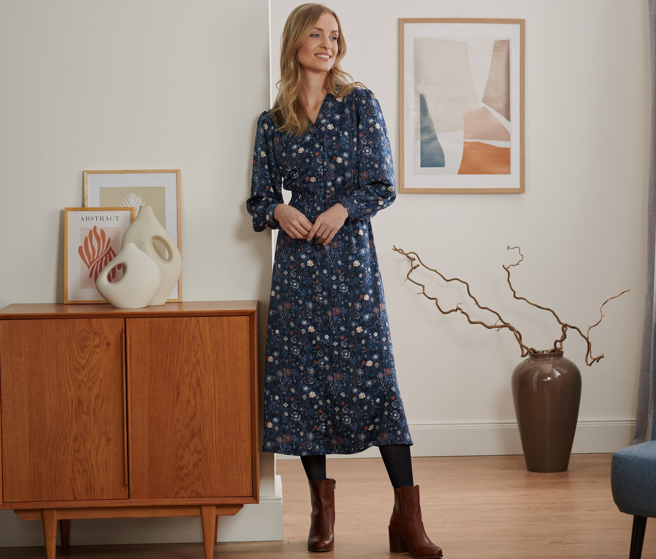 Frau steht im Raum und trägt ein florales Midikleid.