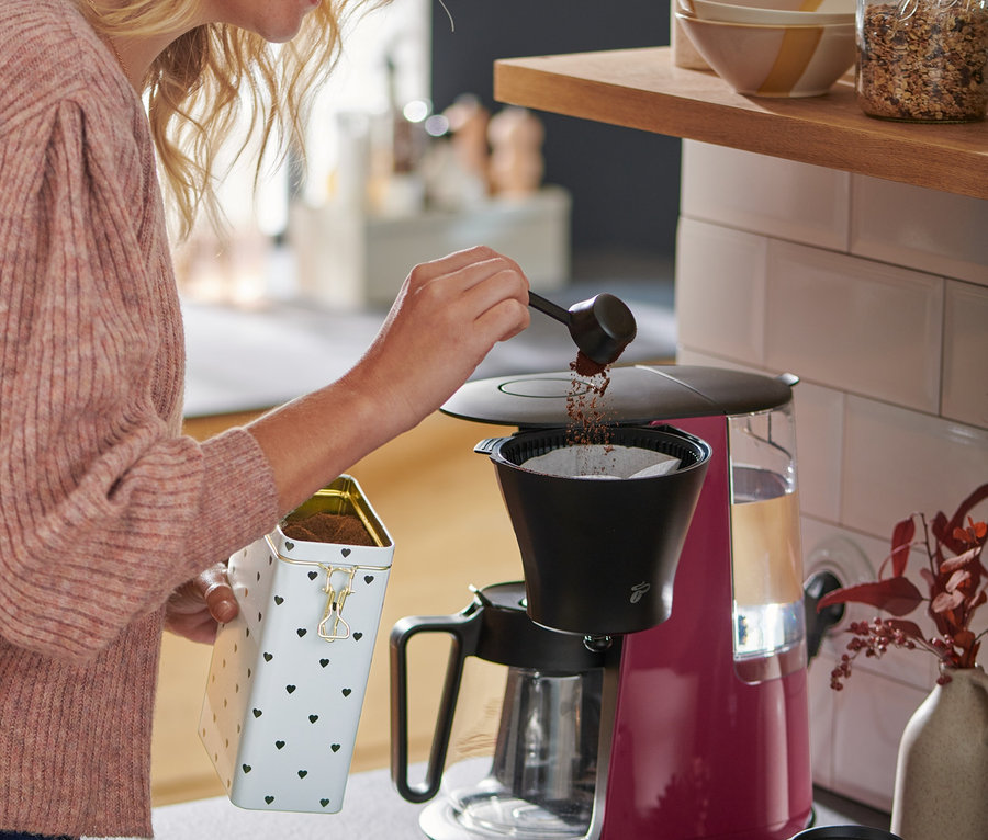 Frau mit blonden Haaren füllt Kaffee in eine »Let's Brew« Filterkaffeemaschine, berry.