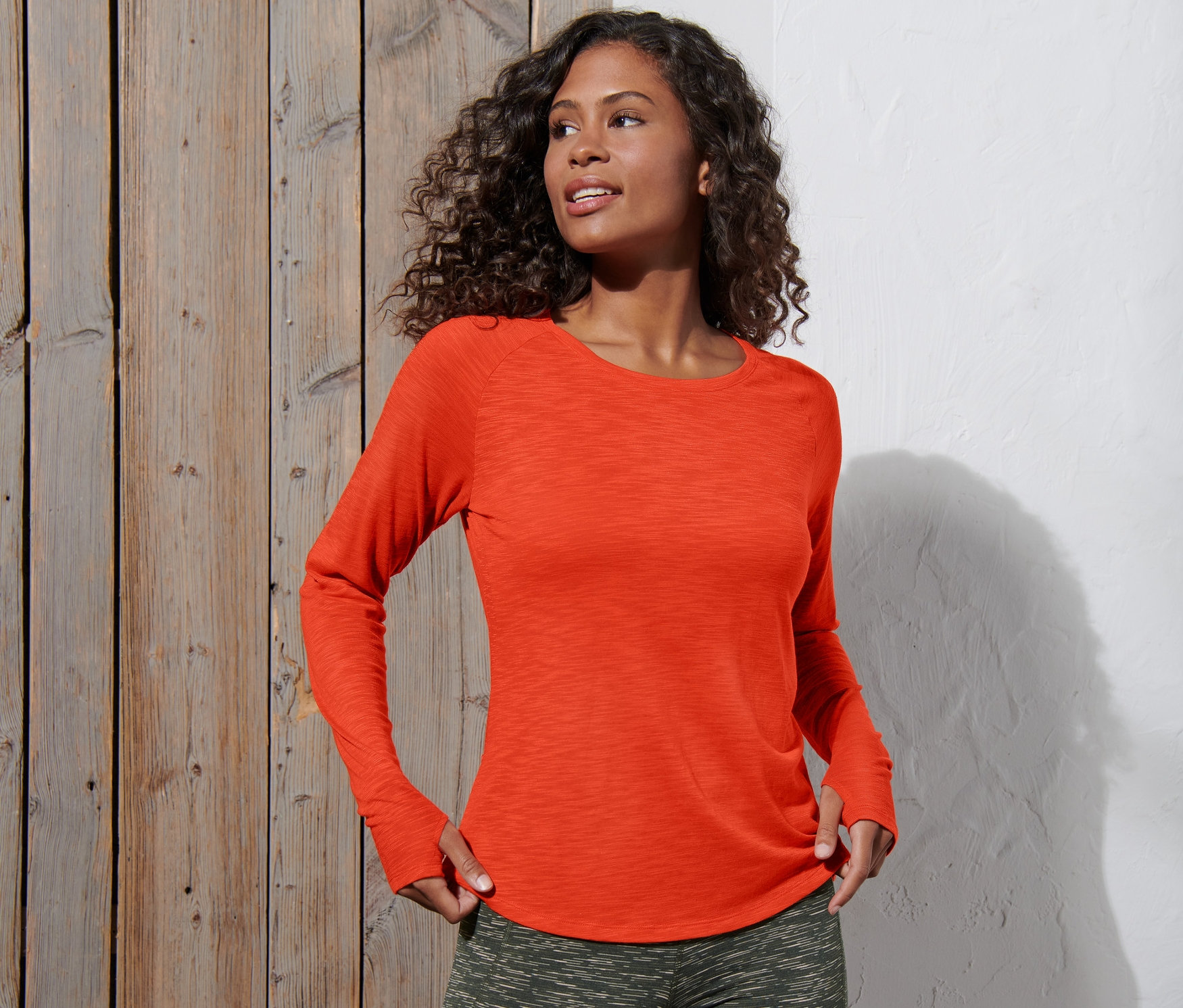 Frau trägt ein orangefarbenes Langarm-Sportshirt.