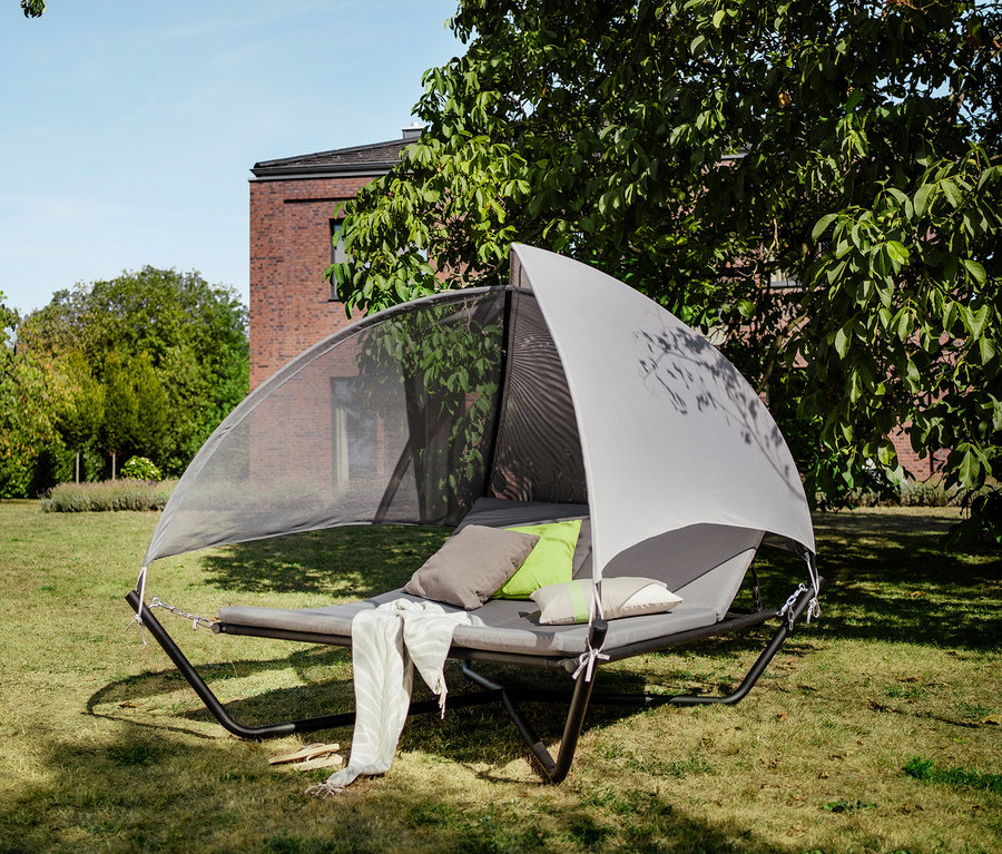 Sonnenbett Outdoor-Liege mit Baldachin und Kissen steht auf einer Wiese.