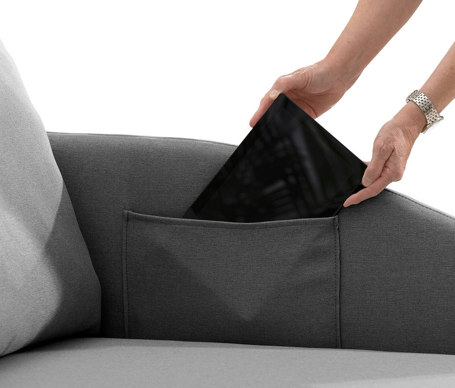 Hände legen Tablet in die Tasche der anthrazitfarbenen Polsterliege »Tobi«.
