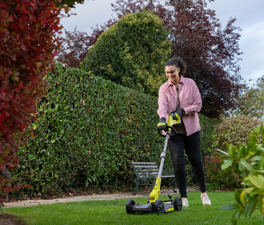 Frau mäht Rasen mit einem RYOBI 18 V One+ Akku-City-Rasenmäher-Set »RY18LMC30A-120«.