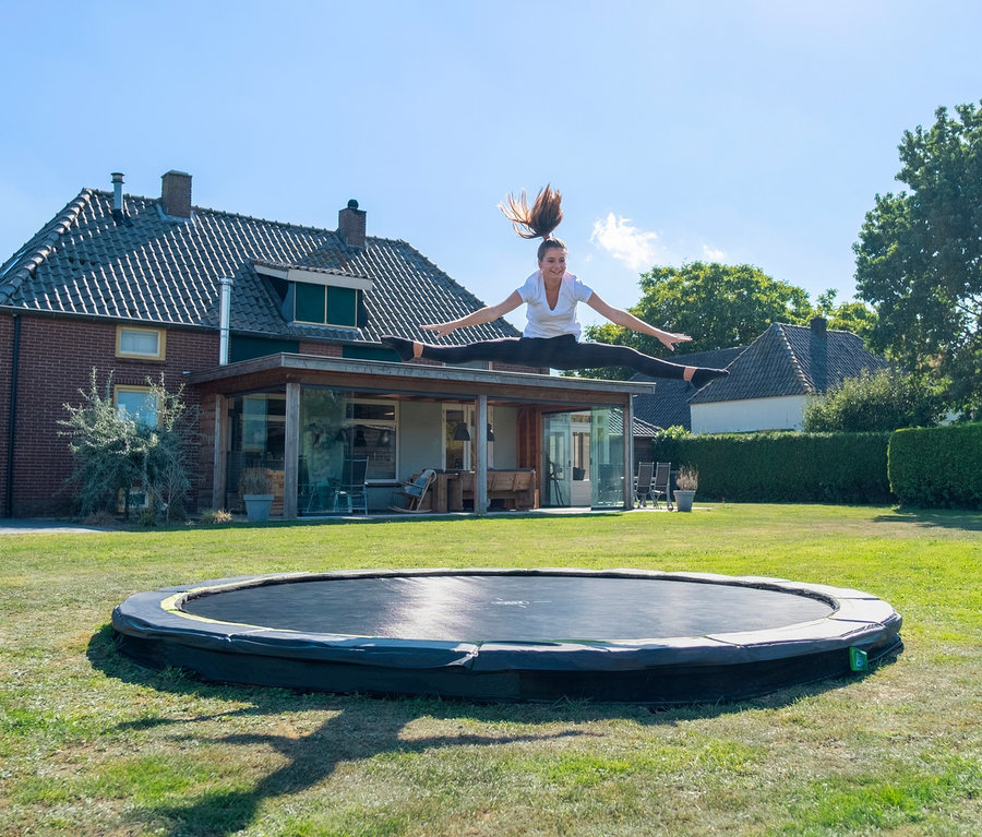 Junge Frau macht einen Spagat in der Luft über dem EXIT Bodentrampolin »Silhouette sports«, Ø ca. 427 cm.