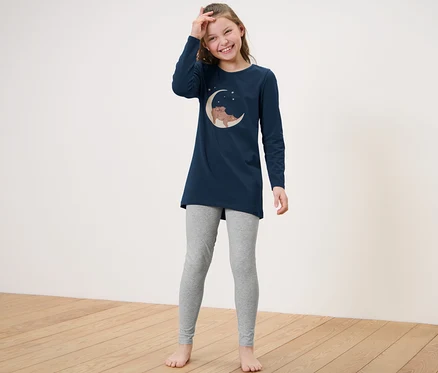 Lächelndes Mädchen posiert in einem Kinder-Pyjama.