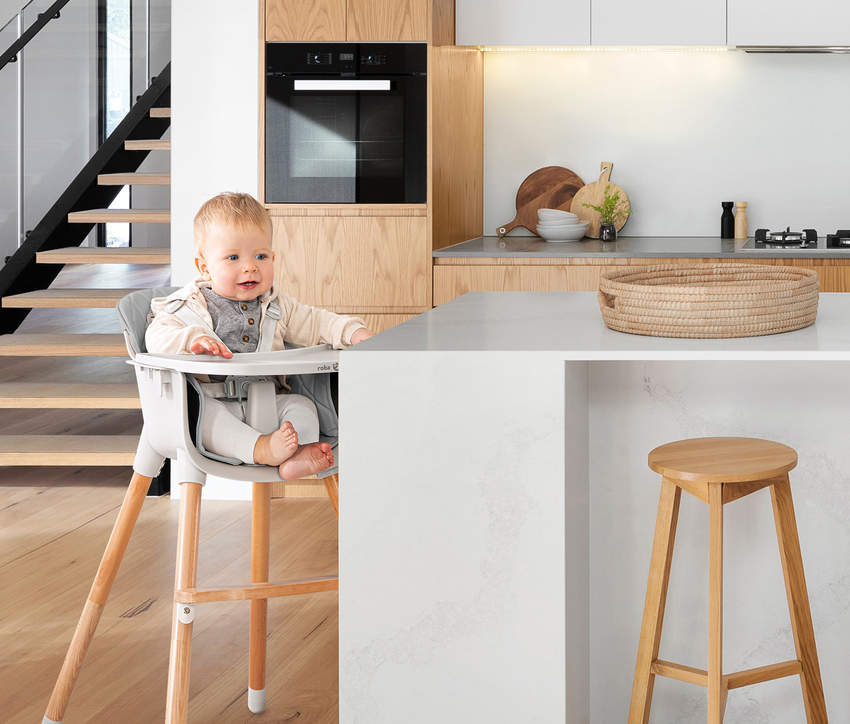 Ein Baby sitzt in einem roba 2-in-1-Hochstuhl »Style Up wood« in einer modernen Küche.