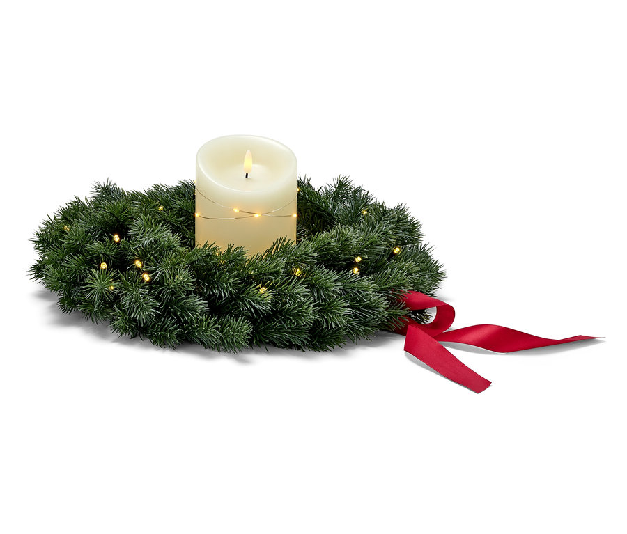 LED-Tannenkranz mit roter Schleife um eine weiße Kerze gewickelt.