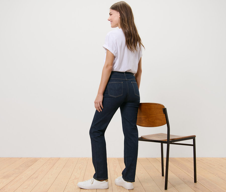 Eine Frau steht mit dem Rücken zur Kamera und trägt eine Straight Jeans – Fit »Kira«, ein weißes T-Shirt und Turnschuhe.