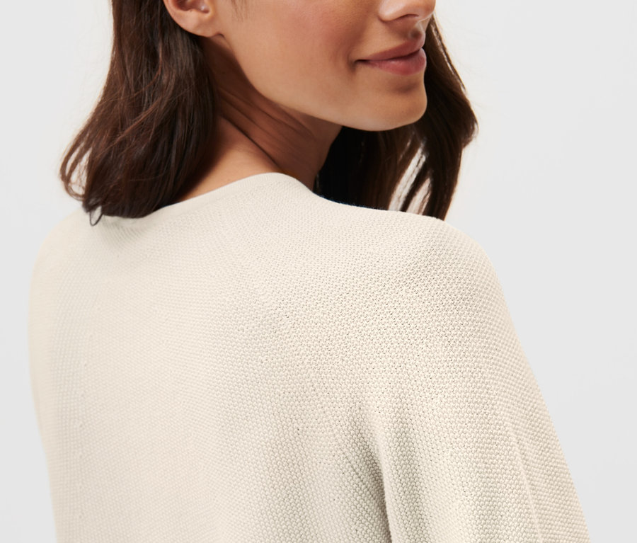 Frau trägt einen cremeweißen Strickpullover.