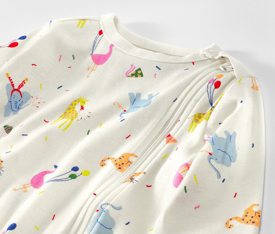 Detailansicht eines weißen Baby-Schlafanzugs mit Allover-Tierprint.