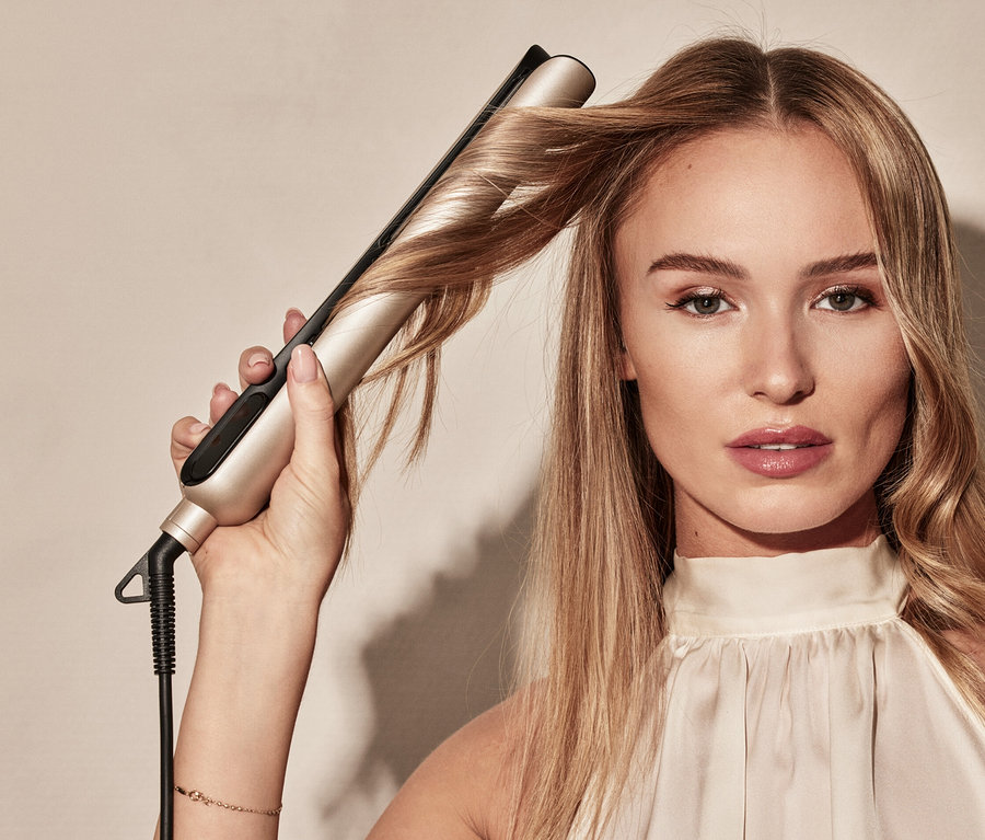 Blonde Frau glättet Haare mit Silk'n Infrarot Glätteisen »SilkyStraight«.