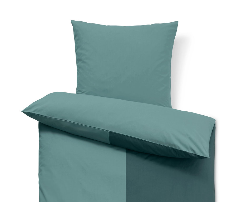 Detail einer Premium Baumwoll-Bettwäsche mit zwei blaugrünen Farbtönen, bestehend aus Kissen und Bettdecke.