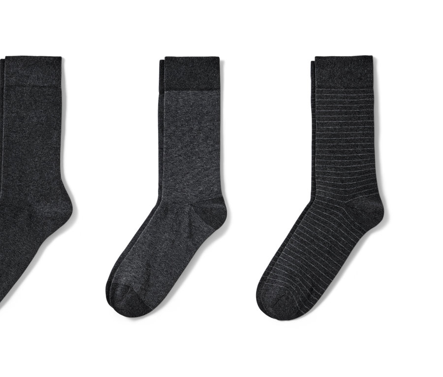 Drei Paar anthrazitfarbene Socken liegen nebeneinander auf einem weißen Hintergrund.