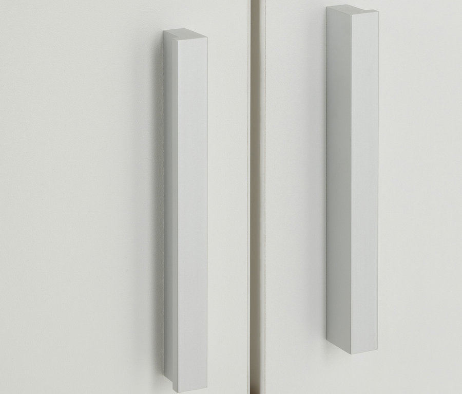 Detail einer weißen Nonza Vitrine mit langen silbernen Griffen und einer unteren braunen Schublade.