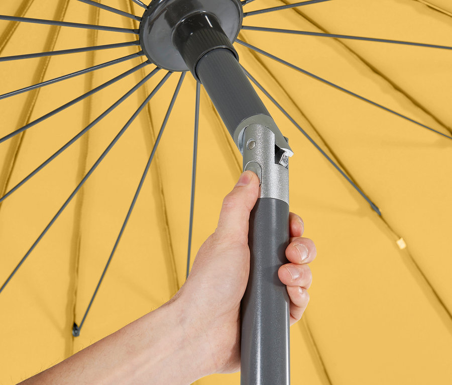 Eine Hand drückt einen Knopf an einer grauen Stange des gelben Leco Aluminium-Sonnenschirms »Shanghai«.