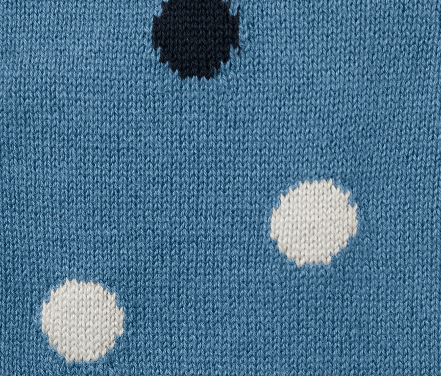 Detailansicht einer blauen Kleinkind-Strickjacke mit schwarzen und weißen Punkten.