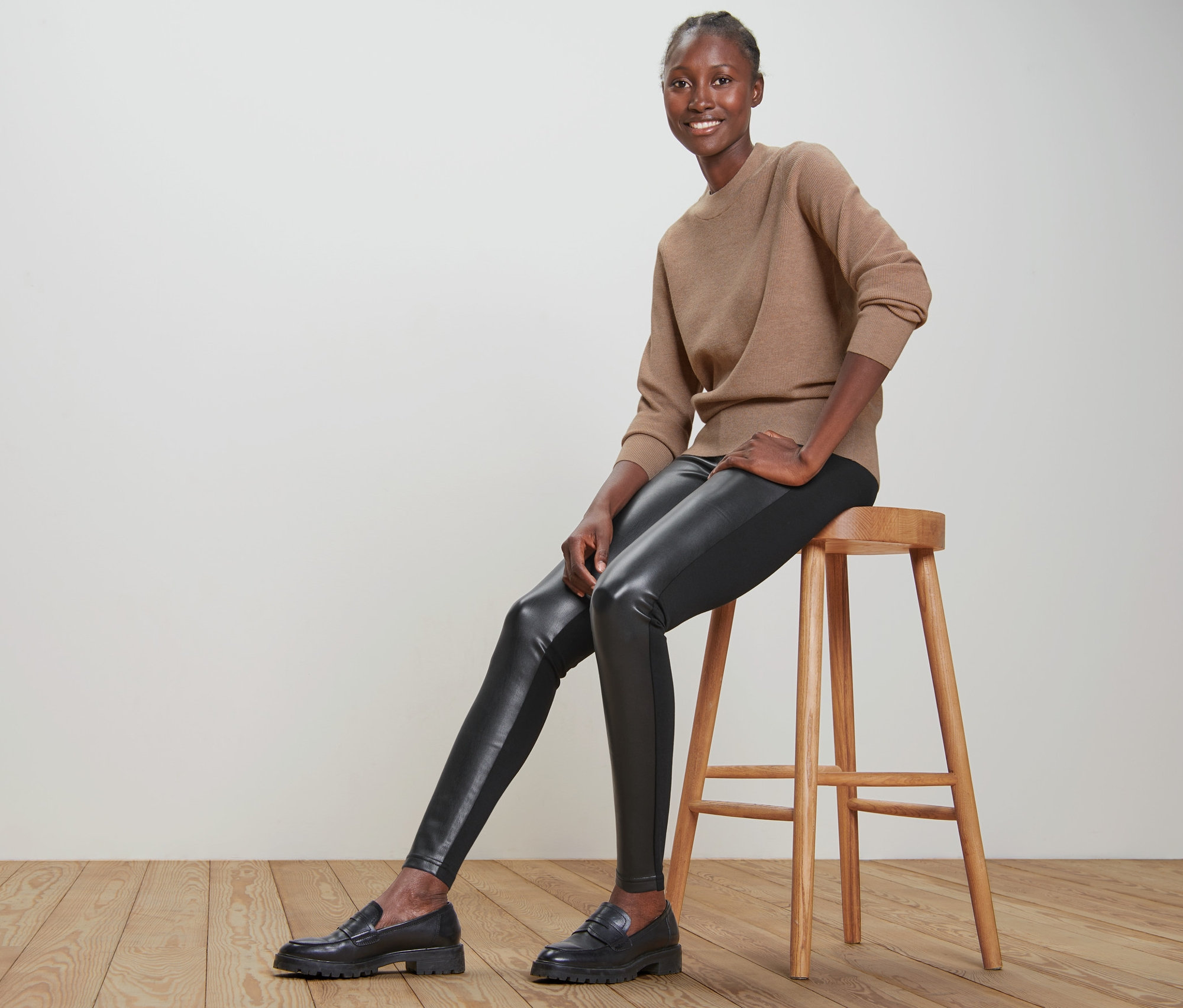 Frau sitzt auf einem Hocker und trägt Leggings im Materialmix.