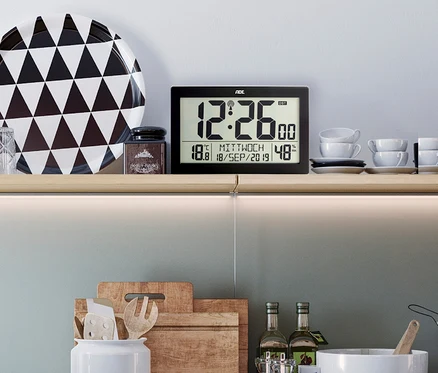 ADE XL-Funkwanduhr mit Thermometer und Hygrometer auf einem Regal.