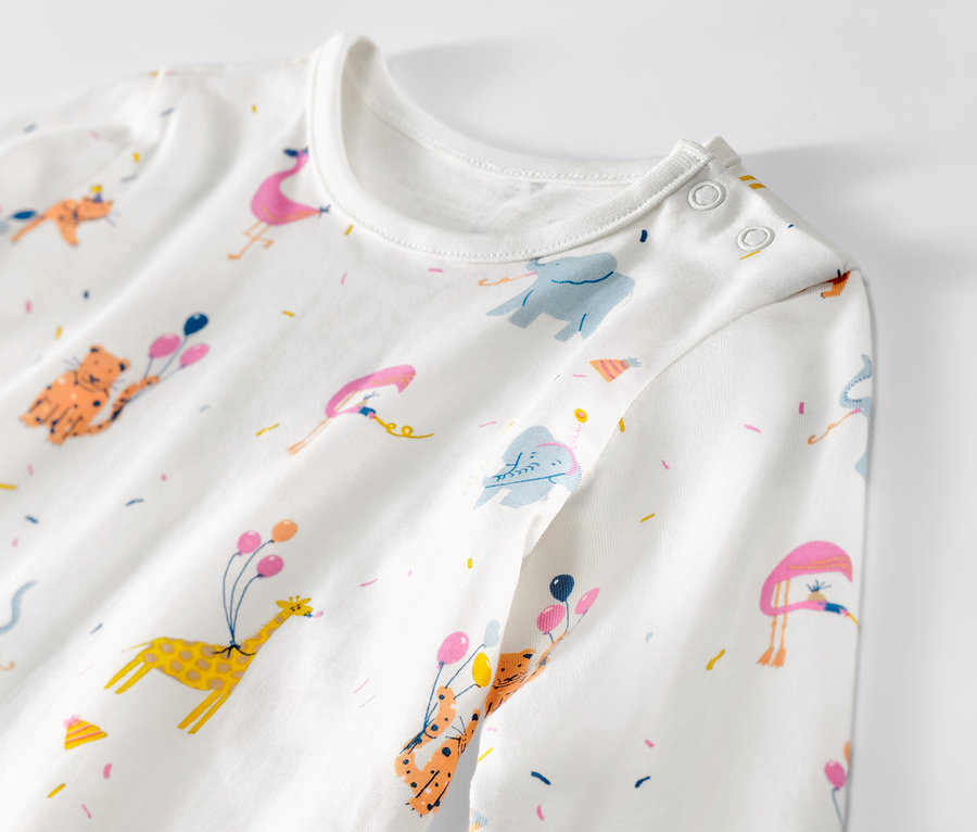 Detailansicht eines Kinder-Pyjamas mit Tiermotiven, Ballons und Konfetti.
