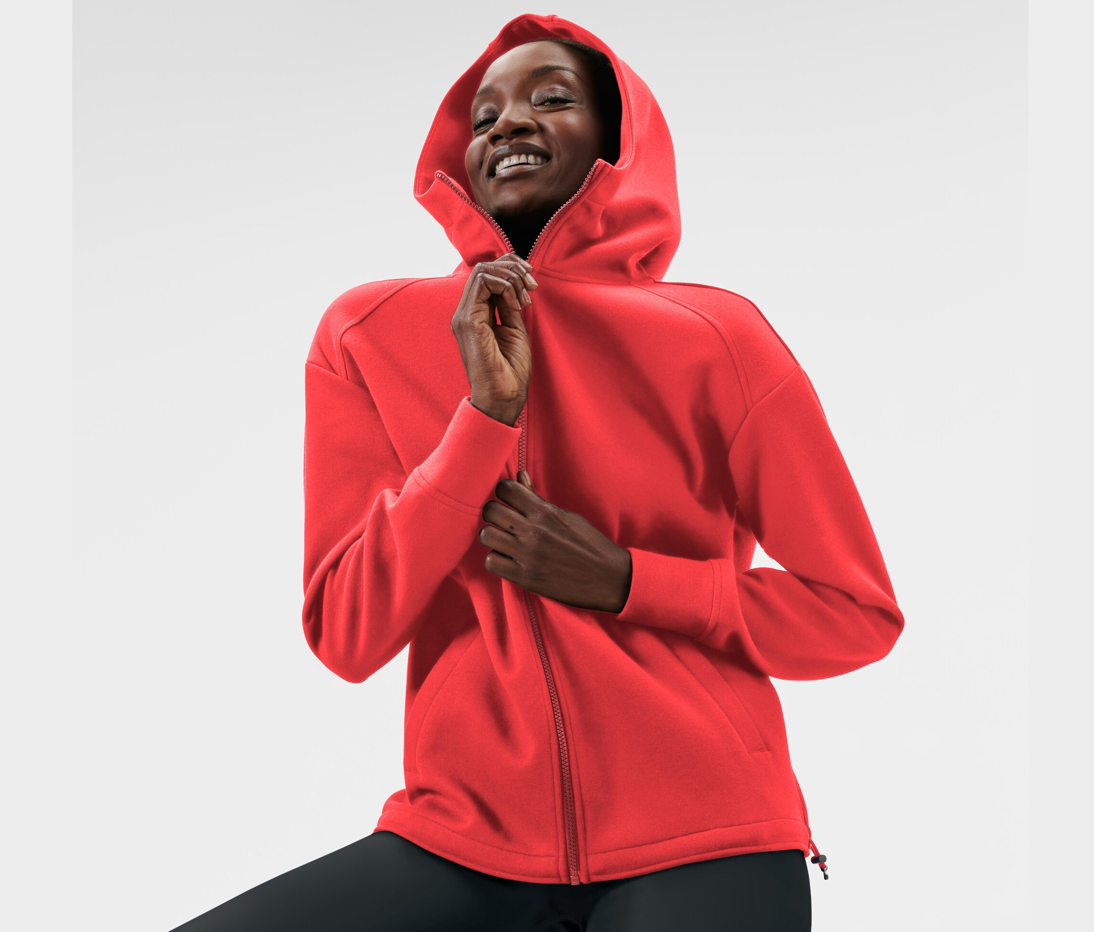 Frau schliesst rote Kapuzen-Sweatjacke.