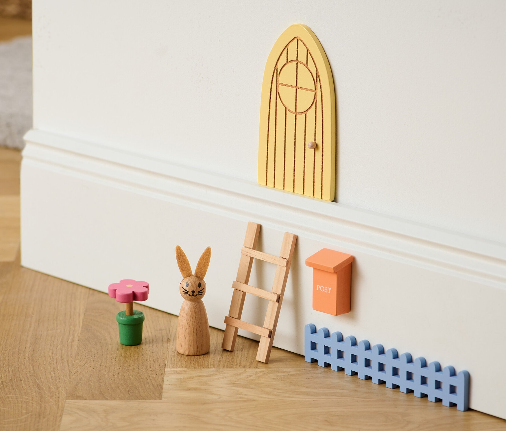 Gelbes Oster-Wichteltür-Set mit Holzleiter, Briefkasten, Zaun, Blume und Hase.