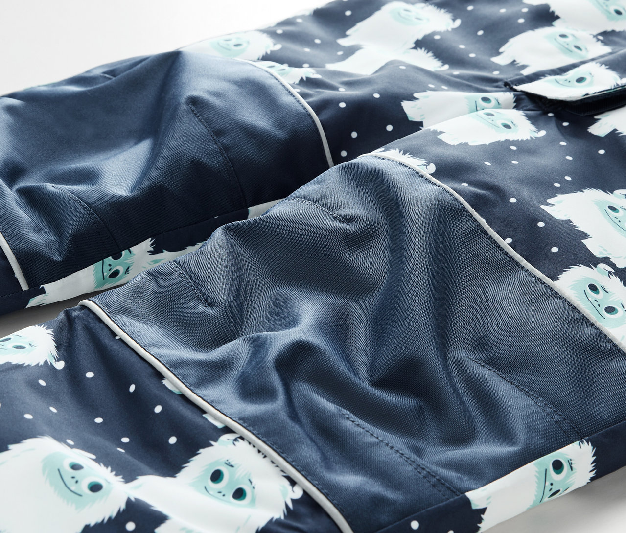 Detail einer blauen Pyjamahose mit weißen Schneemännern und weißen Punkten.
