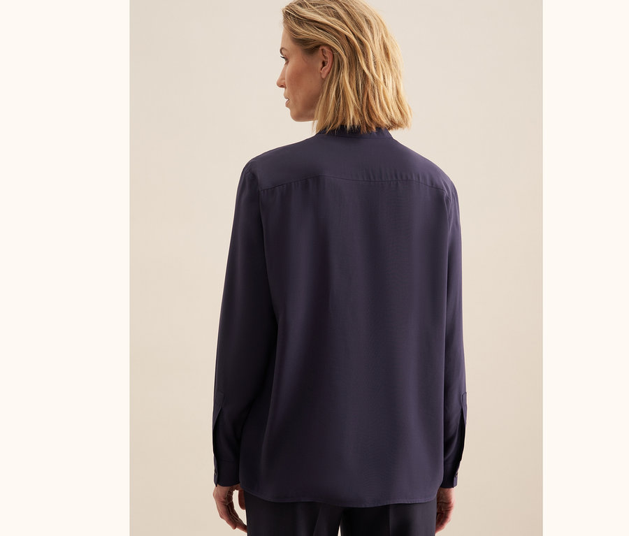 Rückansicht einer blonden Frau, die eine Seidensticker Tunika aus Viskose trägt.