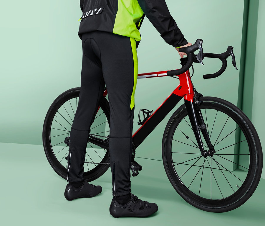 Mann posiert neben einem Fahrrad und trägt eine Velohose.