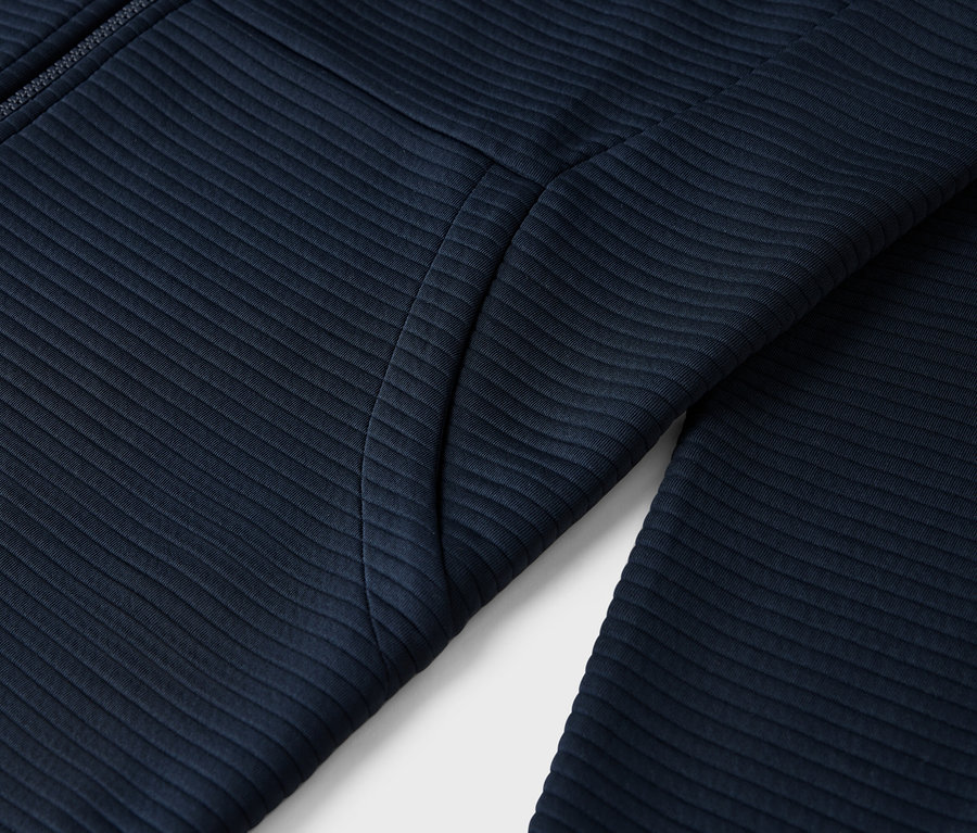 Detailaufnahme einer marineblauen, gerippten Jacke mit Reißverschluss und Tasche.
