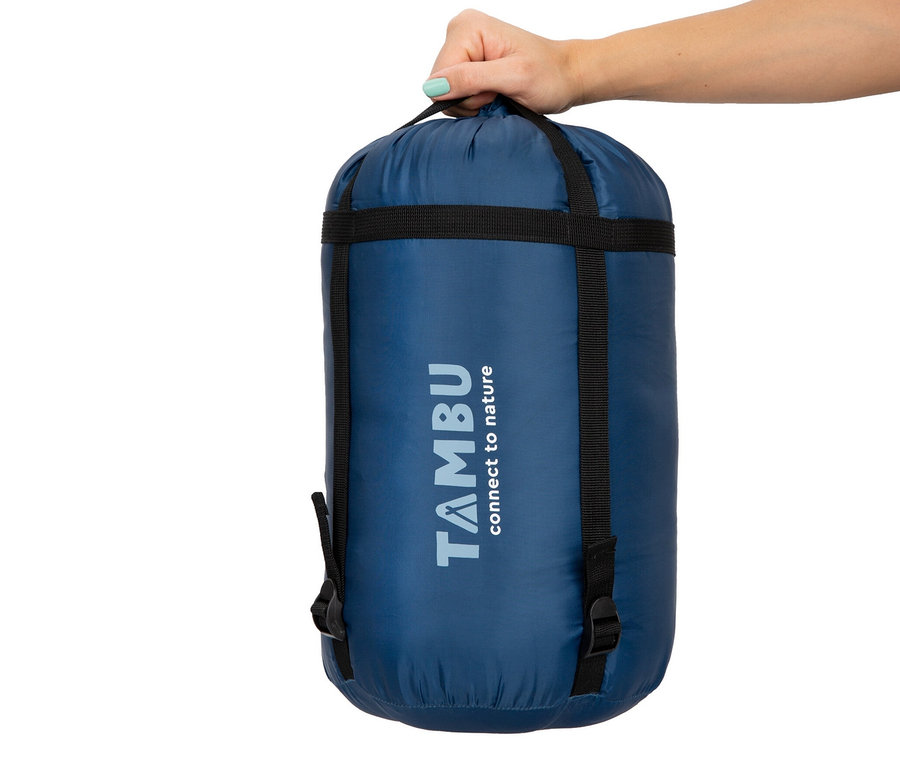 Eine Hand hält einen blauen Packsack für den Tambu Mumienschlafsack »TALU 1500«.