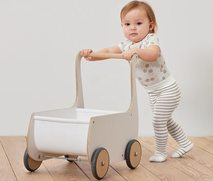 Ein Kleinkind schiebt einen Holzwagen und trägt eine Strumpfhose von 5 Paar Baby-Strumpfhosen.