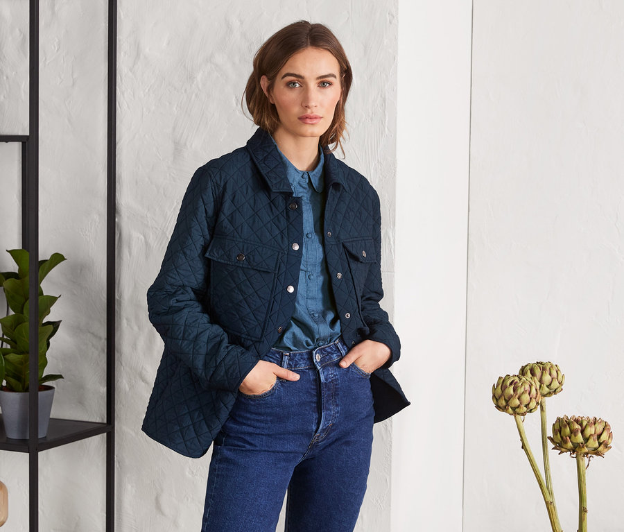 Frau trägt ein Overshirt, ein Jeanshemd und Jeans.