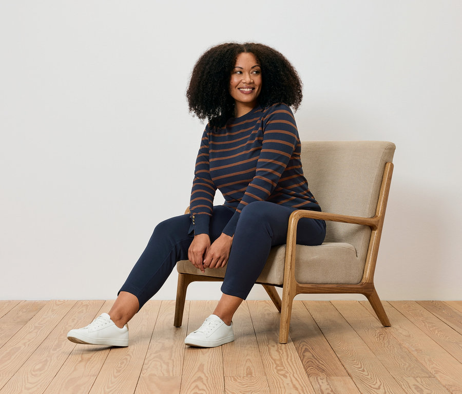 Frau sitzt im Sessel und trägt eine Joggpants.
