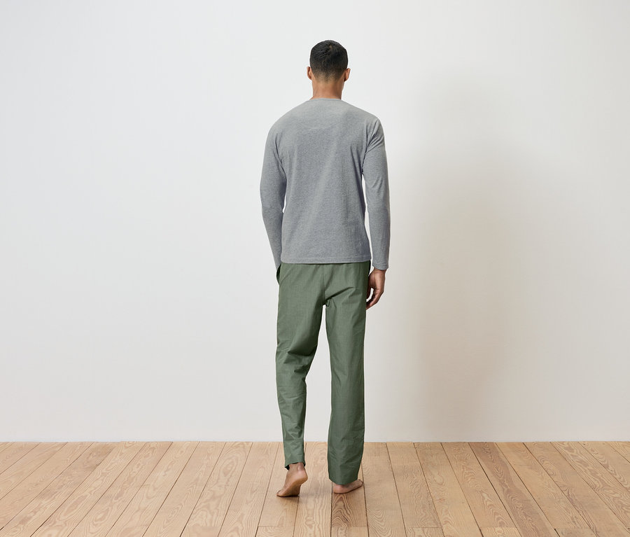 Mann von hinten mit grauem Langarmshirt und grüner Hose.