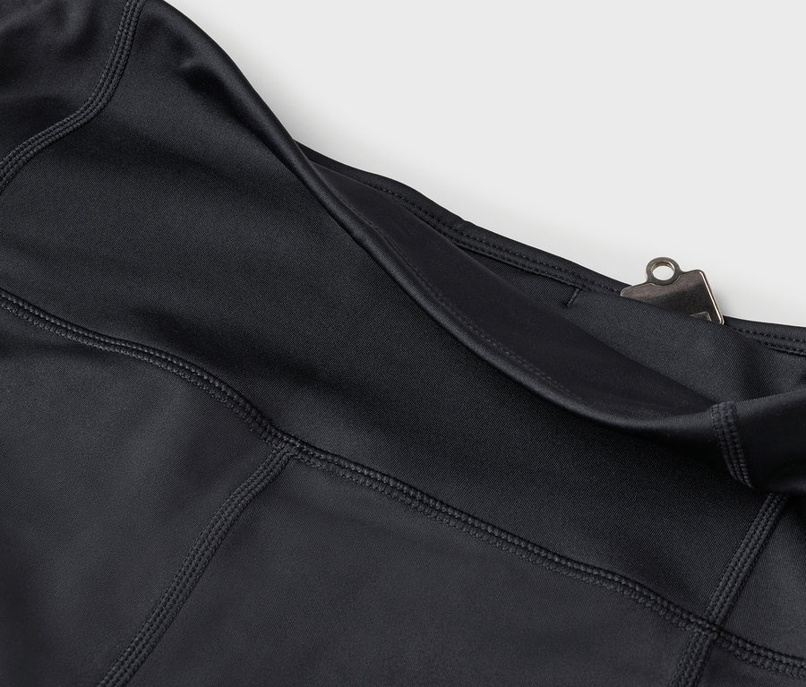Detailaufnahme von schwarzen Leggings mit Tasche und silbernem Clip.