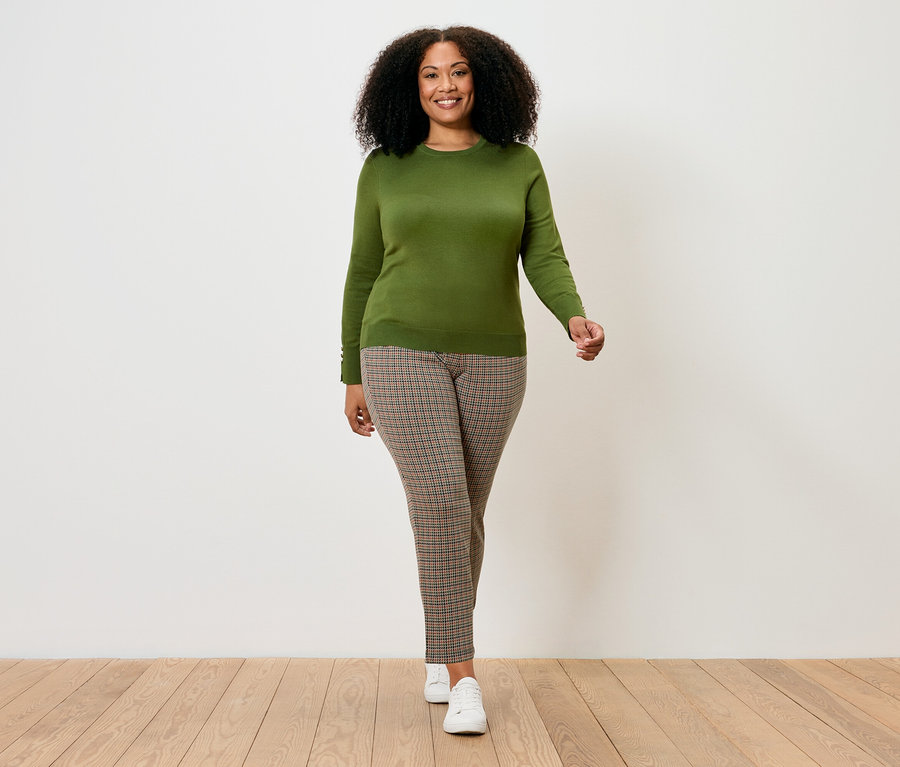 Frau geht und trägt einen hellgrünen Feinstrickpullover.