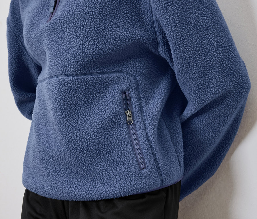 Detailaufnahme eines blauen Fleecepullovers mit Reißverschlusstasche.