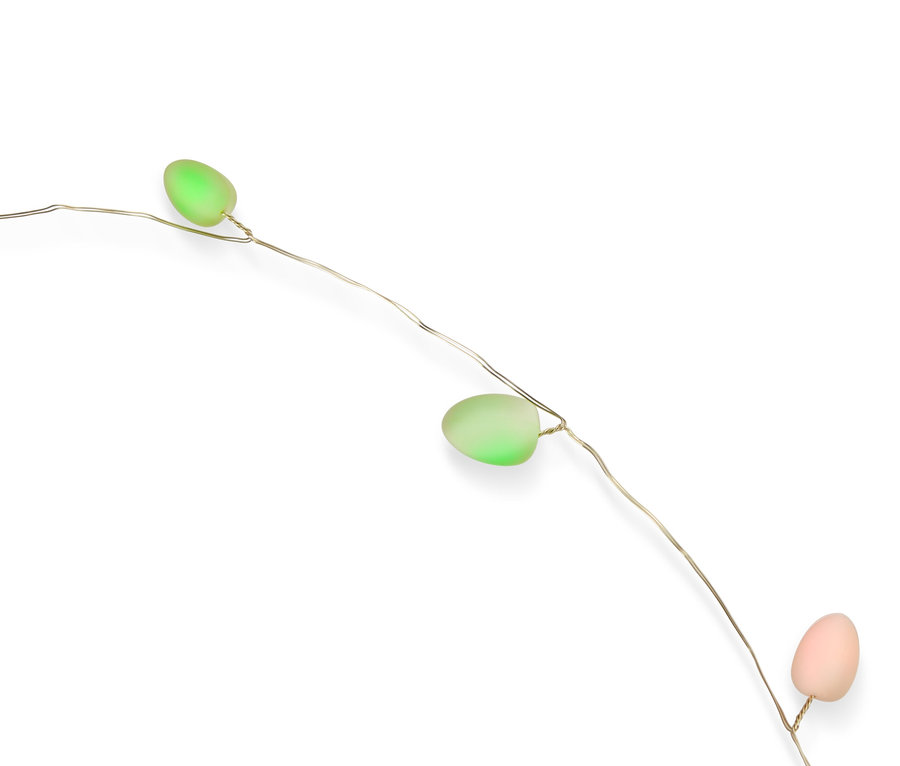 Dekorative Lichterkette mit drei pastellfarbenen Ostereiern (grün, rosa) auf weißem Hintergrund.