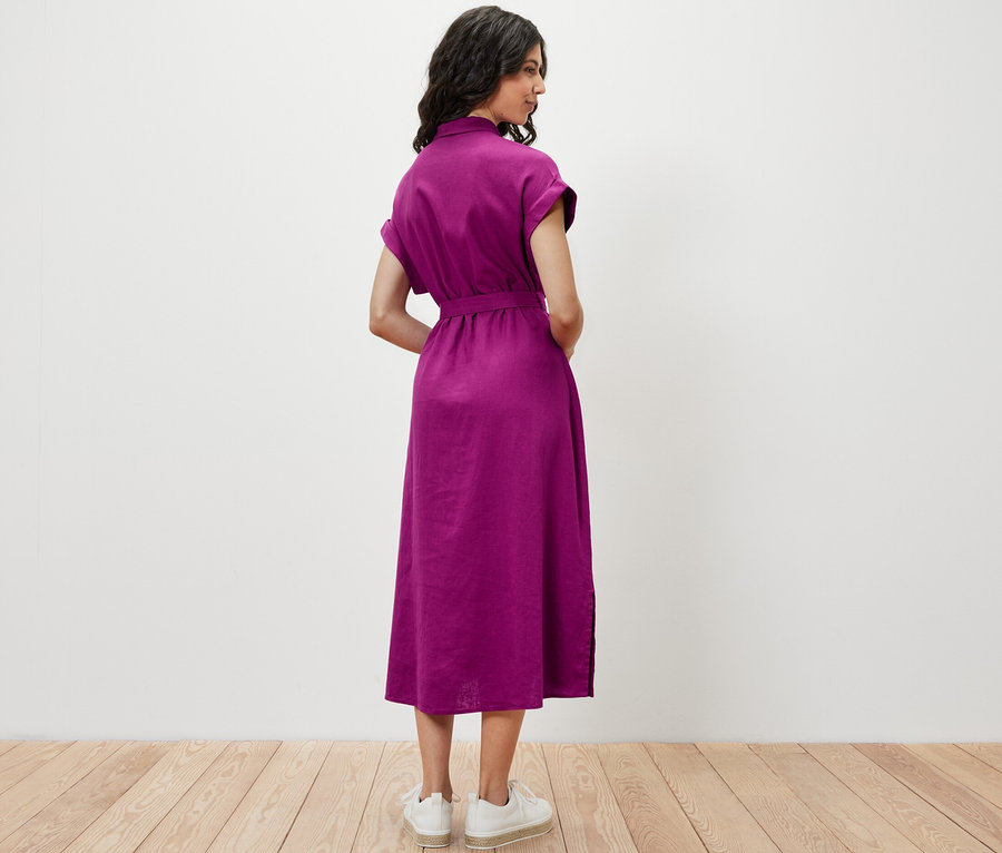 Eine Frau steht mit dem Rücken zur Kamera und trägt ein Leinenkleid.