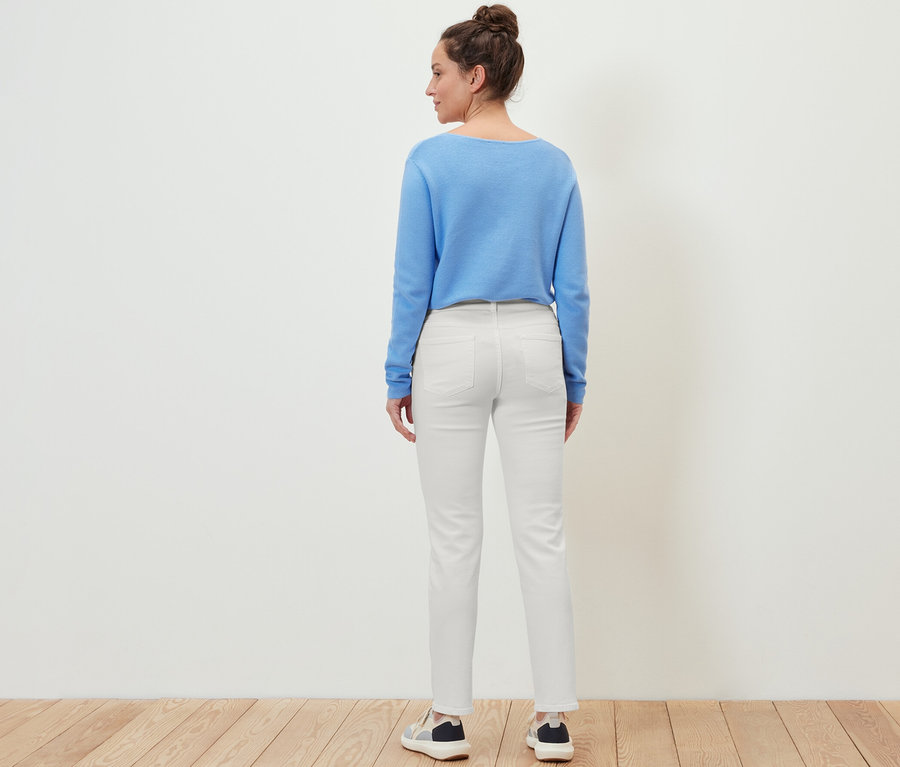 Eine Frau steht mit dem Rücken zur Kamera und trägt eine Jeans ‒ Fit »Kira«, einen blauen Pullover und Turnschuhe.