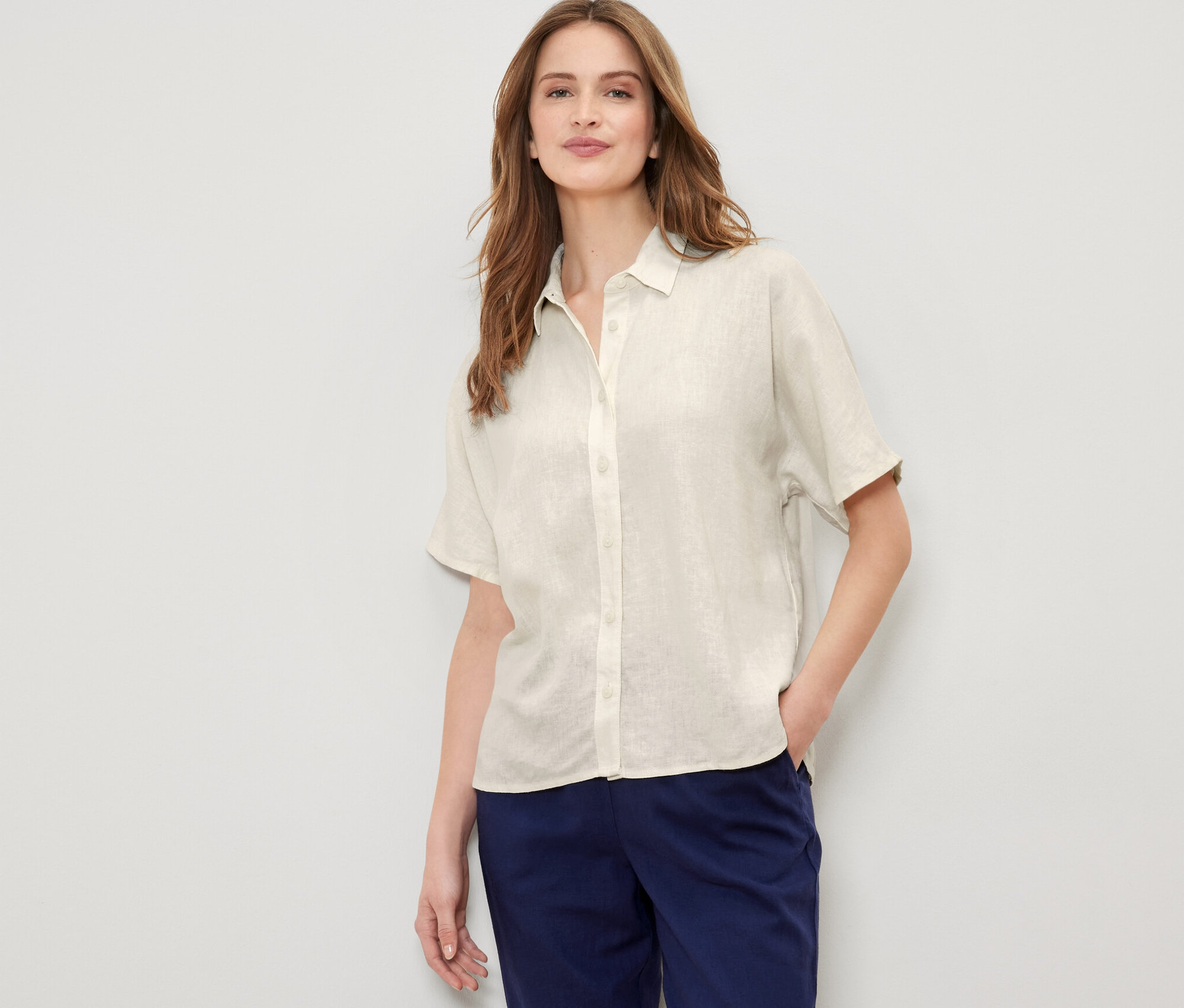 Frau posiert in cremeweißer Leinenbluse.