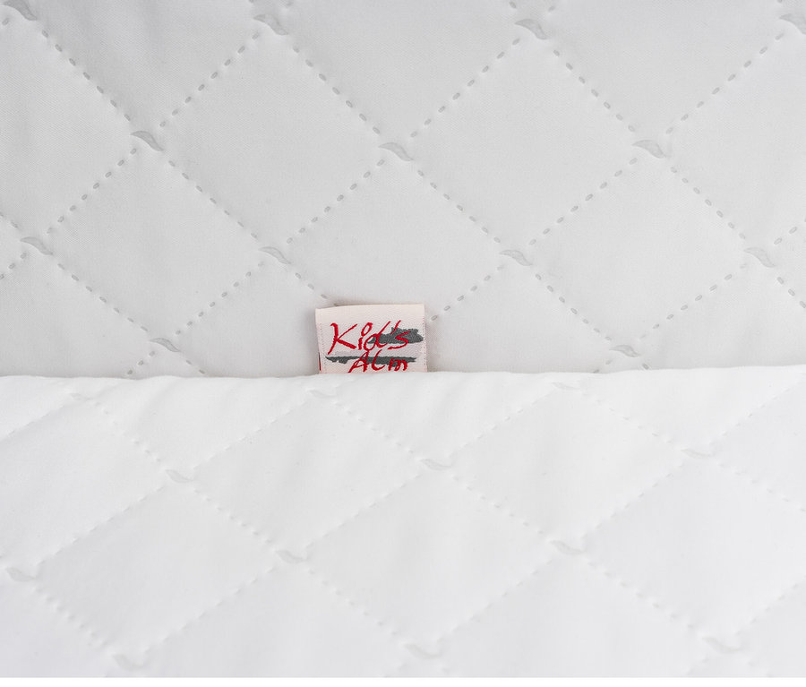 Detail eines weißen Steppstoffs mit kleinem Etikett.