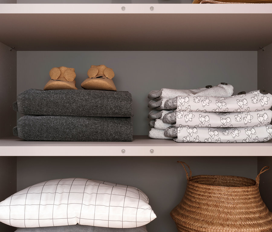 Im Schrank »Alkmaar« liegen Decken, Schühchen, Kissen und ein Korb.