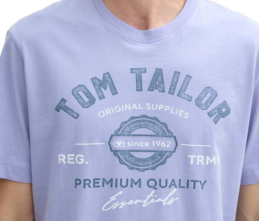 Nahaufnahme eines Mannes in einem hellvioletten T-Shirt mit "Tom Tailor" Aufdruck.