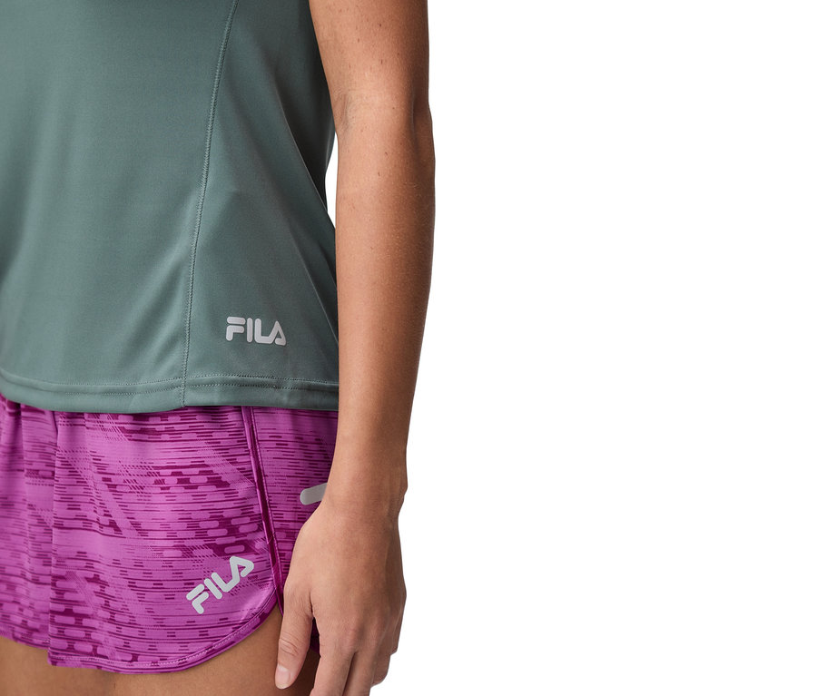 Nahaufnahme einer Frau, die ein grünes Fila-Top und violette Shorts trägt.