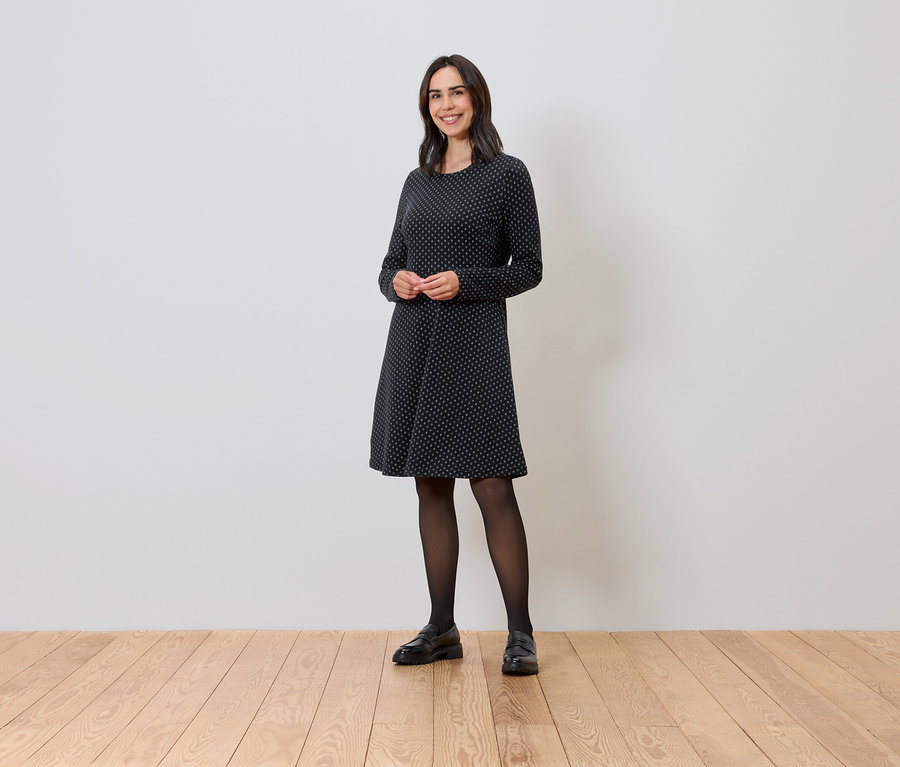 Frau steht und trägt ein glitzerndes Jacquard-Kleid.