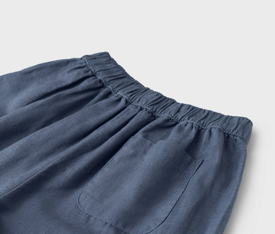 Detailaufnahme einer blauen Hose mit Gummibund und aufgesetzter Tasche.