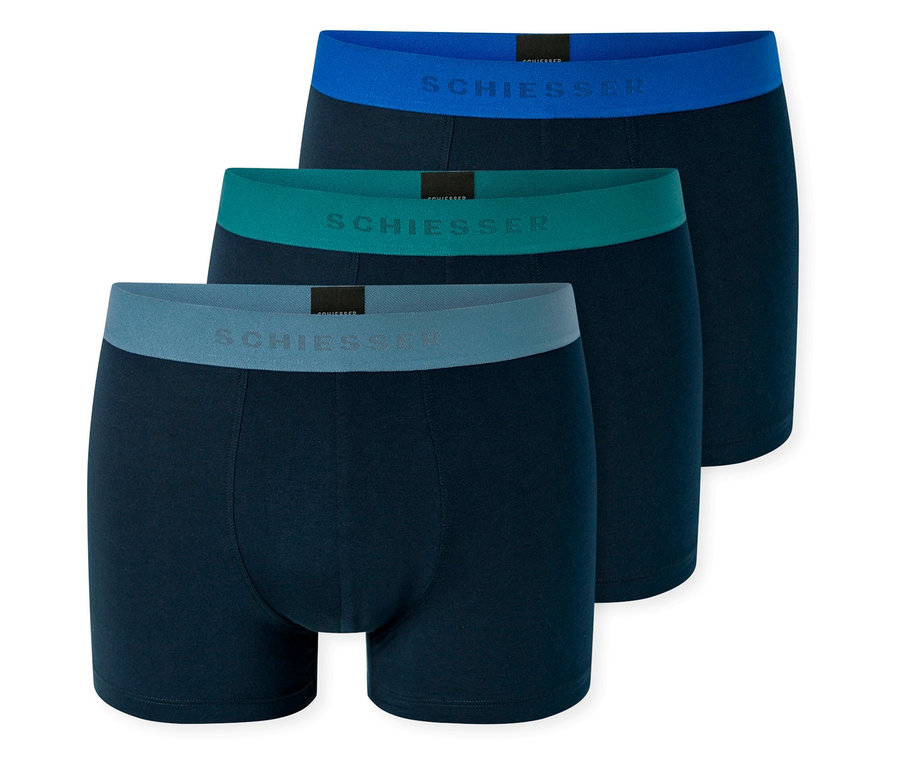 Drei marineblaue Boxershorts der Marke Schiesser mit blauem, türkisfarbenem und grauem Bund.