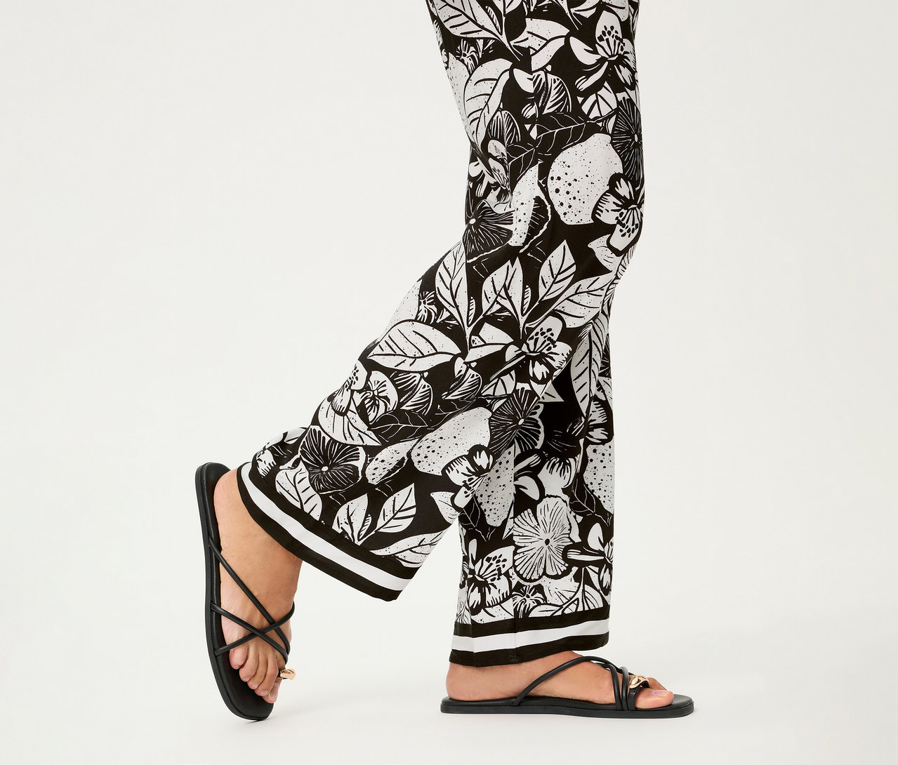 Beine in Olsen Wide Leg Hose mit schwarzem Blumenmuster und Zehensandalen mit Riemchen.