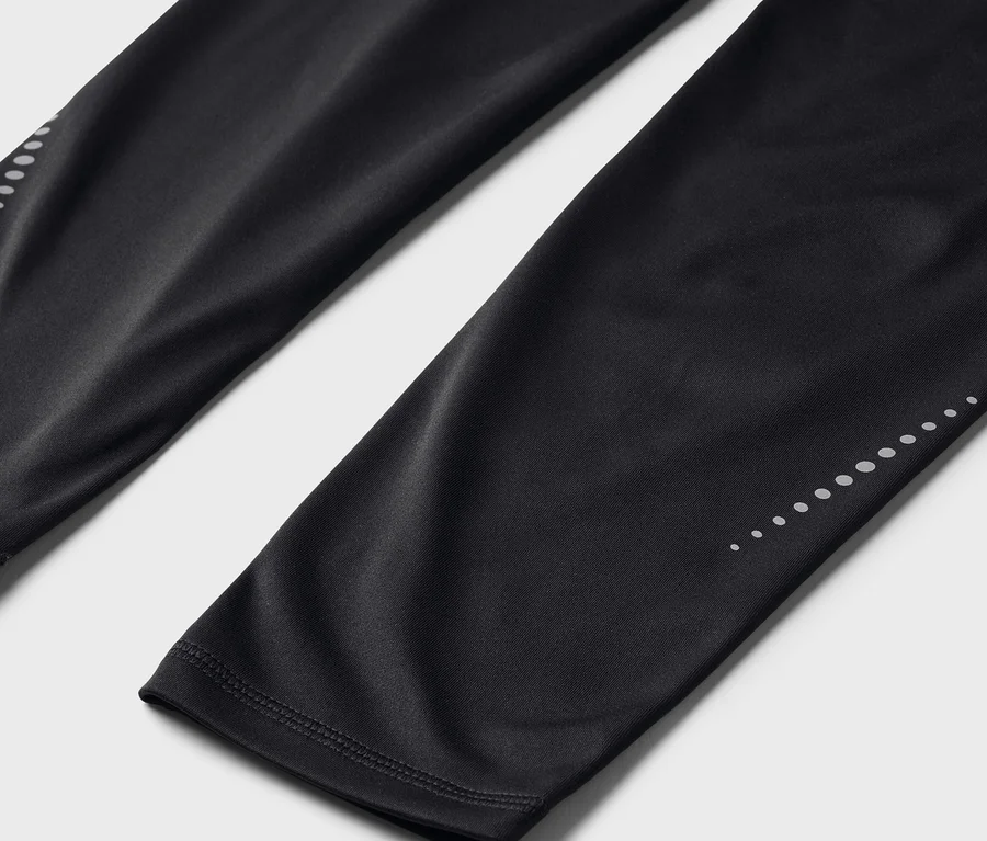 Nahaufnahme von schwarzen Leggings mit reflektierenden Punkten an den Unterschenkeln.